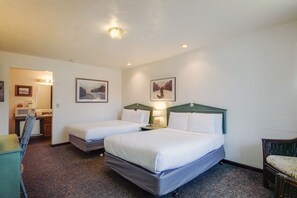 Une chambre d’hôtel avec deux lits, un bureau, une chaise et deux tableaux encadrés au mur.