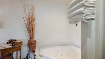 Ein Badezimmer mit einer Badewanne, einem Holzstuhl und einer Korbusvase mit getrockneten Ästen.