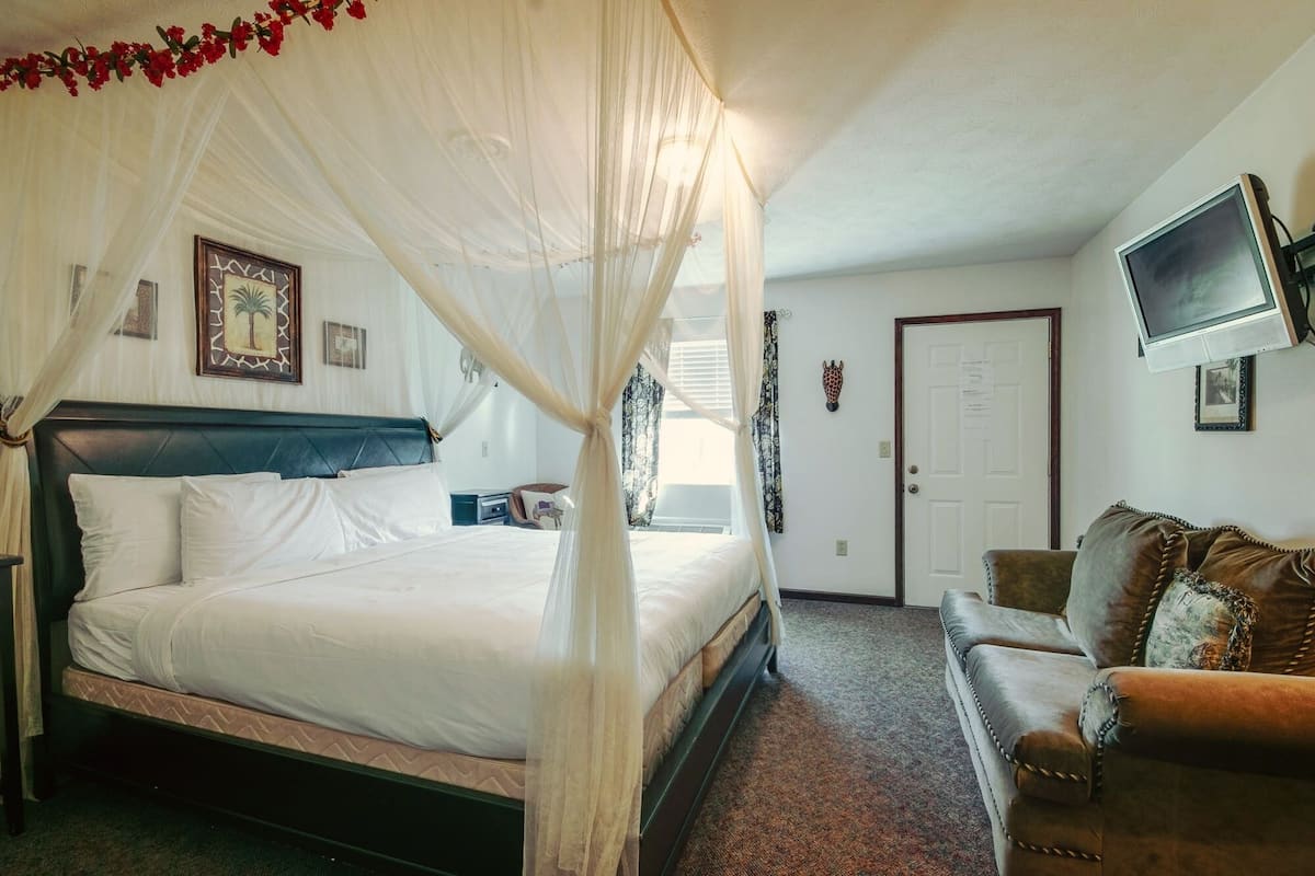 Quarto com cama de dossel, televisão na parede e porta com aviso.