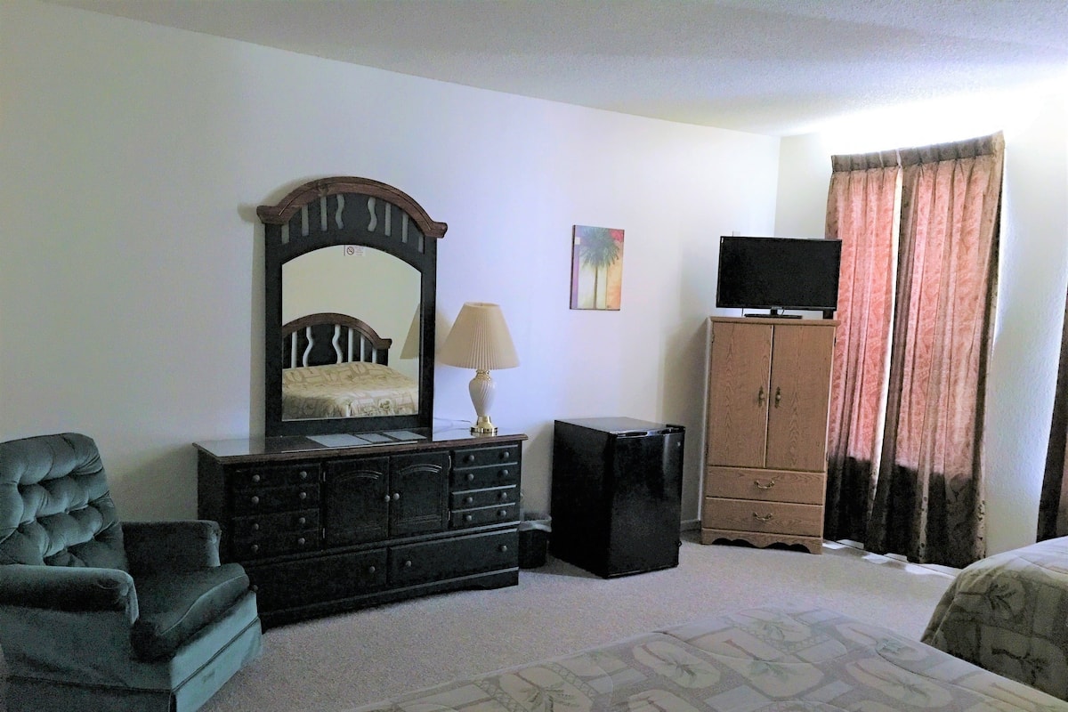 A bedroom with a bed, a dresser, a chair, a television, and a cabinet.