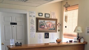 Una recepción con un cuadro enmarcado, una cruz y varios avisos en la pared.