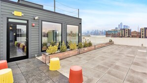 Un bâtiment moderne avec une porte en verre, un panneau de sortie jaune et, en arrière-plan, le profil urbain de la ville.