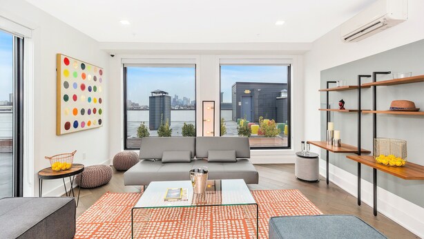Un salon moderne avec un canapé, une table basse et une vue sur le paysage urbain grâce à de grandes fenêtres.