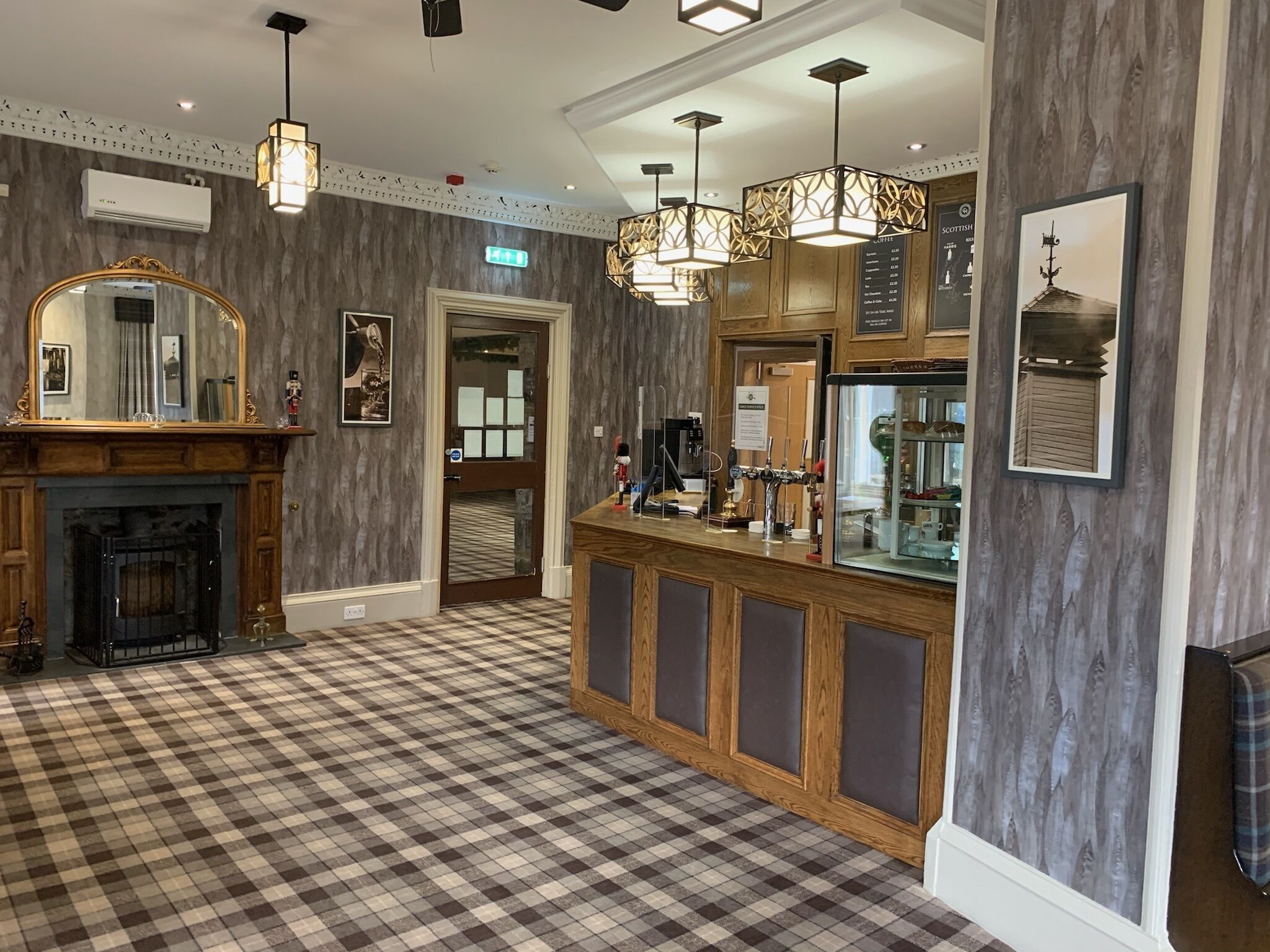 A hotel lobby with a checkered floor, a fireplace, a bar area with a beer tap, and a large mirror.