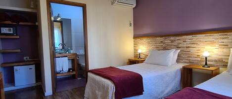 Un dormitorio con dos camas, suelo de madera, lámpara colgante y pared de piedra.