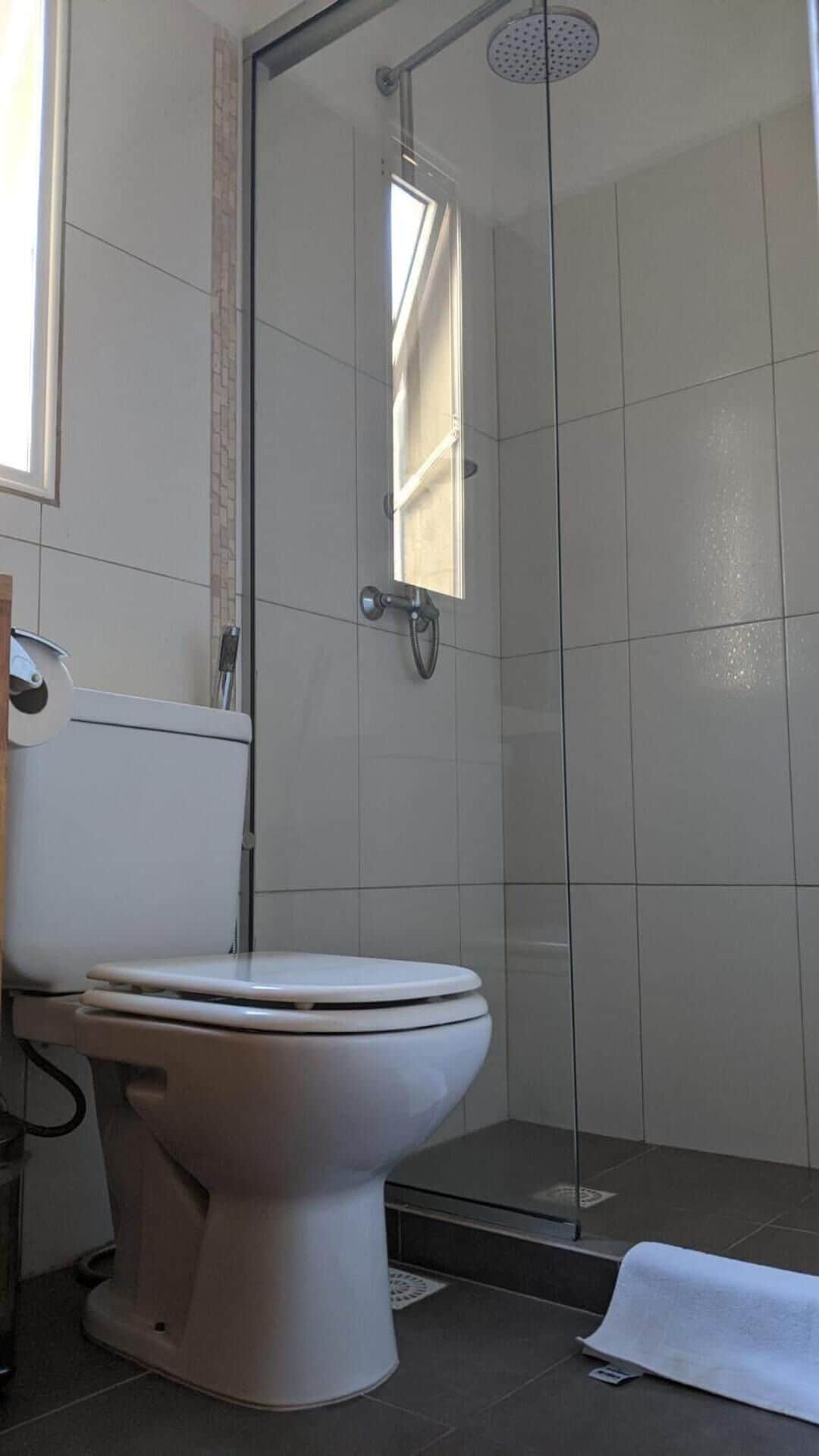 Une salle de bain comprenant des toilettes, un espace douche et une fenêtre.