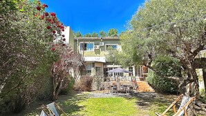 A house with a patio area, a lawn, and a garden with various plants and flowers. - Nova Posada (Colonia del Sacramento)