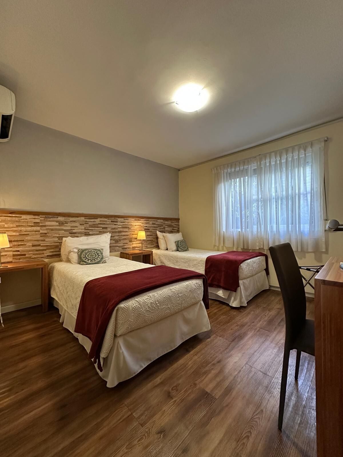 A hotel room with two beds, a desk, and a chair.