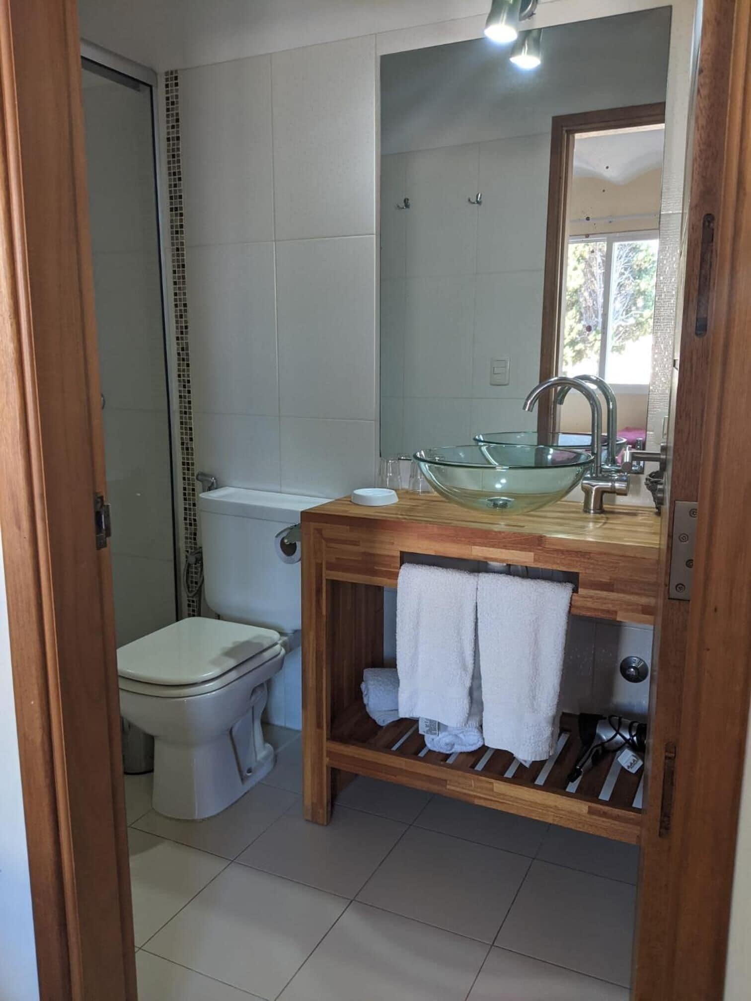 Une salle de bain avec un lavabo en verre, un meuble-lavabo en bois et des toilettes.