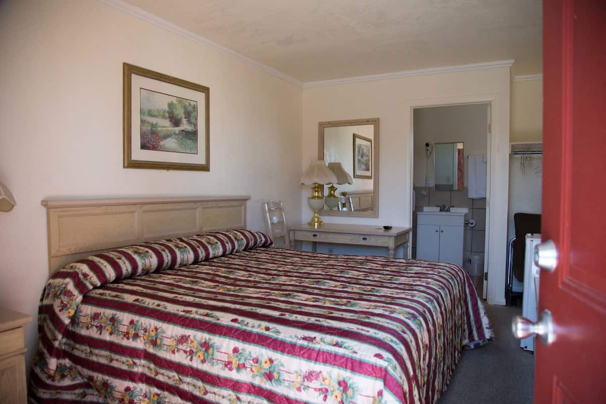 Un dormitorio con una cama grande, un aparador, un espejo y una puerta al baño.