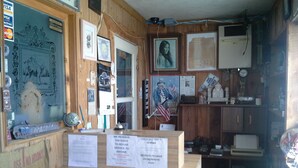 A wooden interior with a reception desk, framed pictures, and various signs. - Boron Motel (Boron)