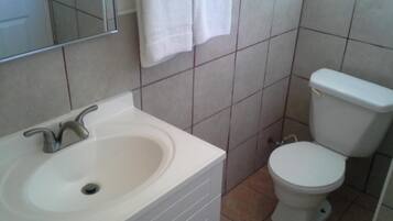 Un baño con lavamanos blanco, inodoro y espejo.
