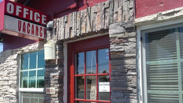 A building with a stone facade, a red door, and a sign indicating an office vacancy. - Boron Motel (Boron)