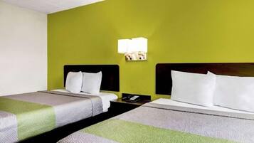 Een hotelkamer met twee bedden, elk met een hoofdeinde, nachtkastje en lamp.