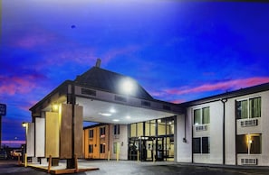 Ein modernes Hotel mit Glastür, überdachter Wartezone und Parkplatz.