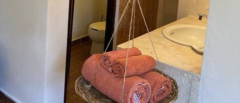 A bathroom with a hanging towel rack, a sink, and a toilet visible in the background.