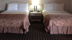 Ett hotellrum med två sängar, var och en med en sänggavel, ett nattduksbord med en lampa och en väckarklocka. Golvet är täckt av en mönstrad matta.