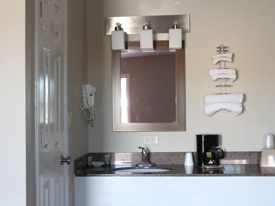 A bathroom with a sink, mirror, towel rack, and a coffee machine.