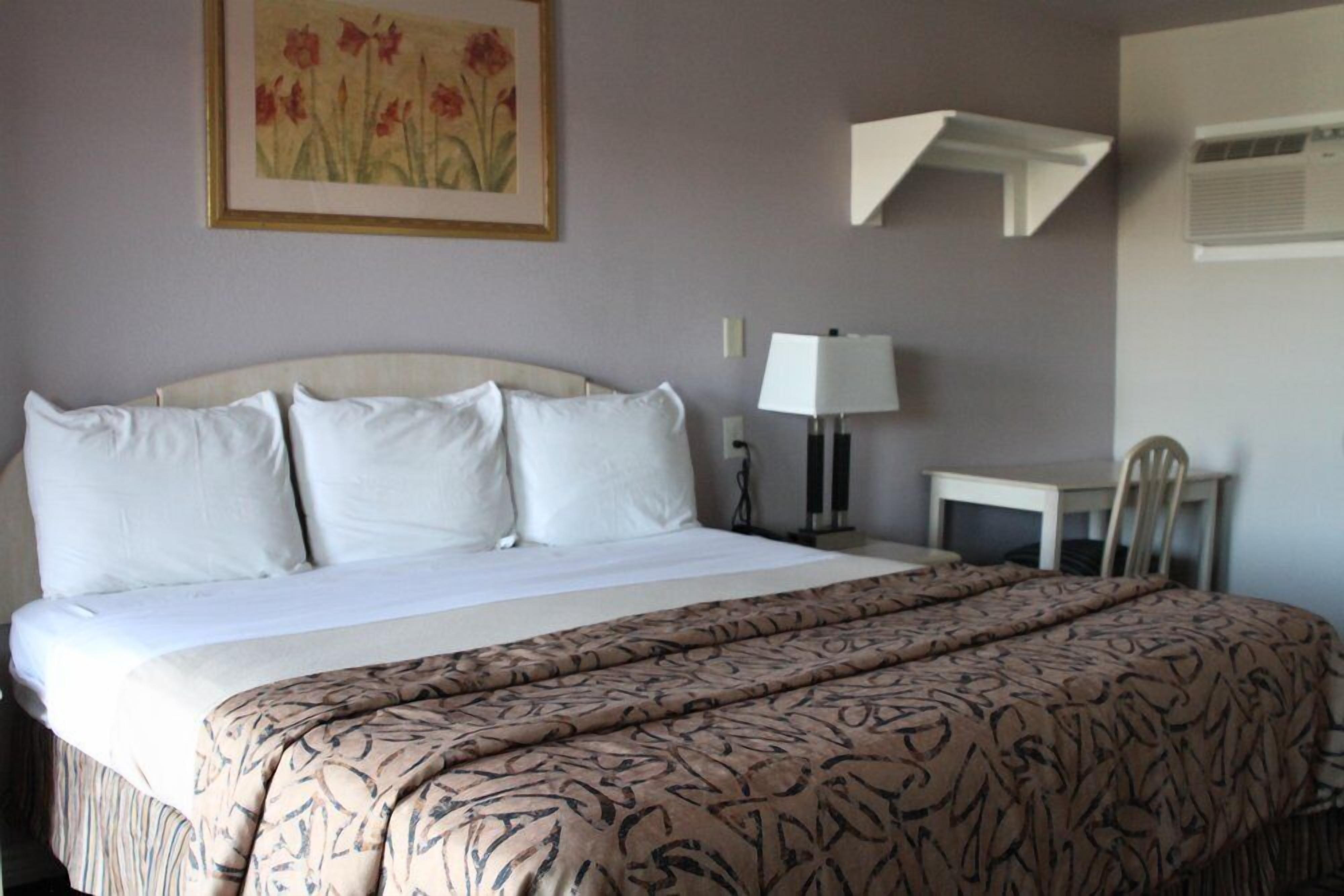 A hotel room with a large bed, a desk, and a chair.