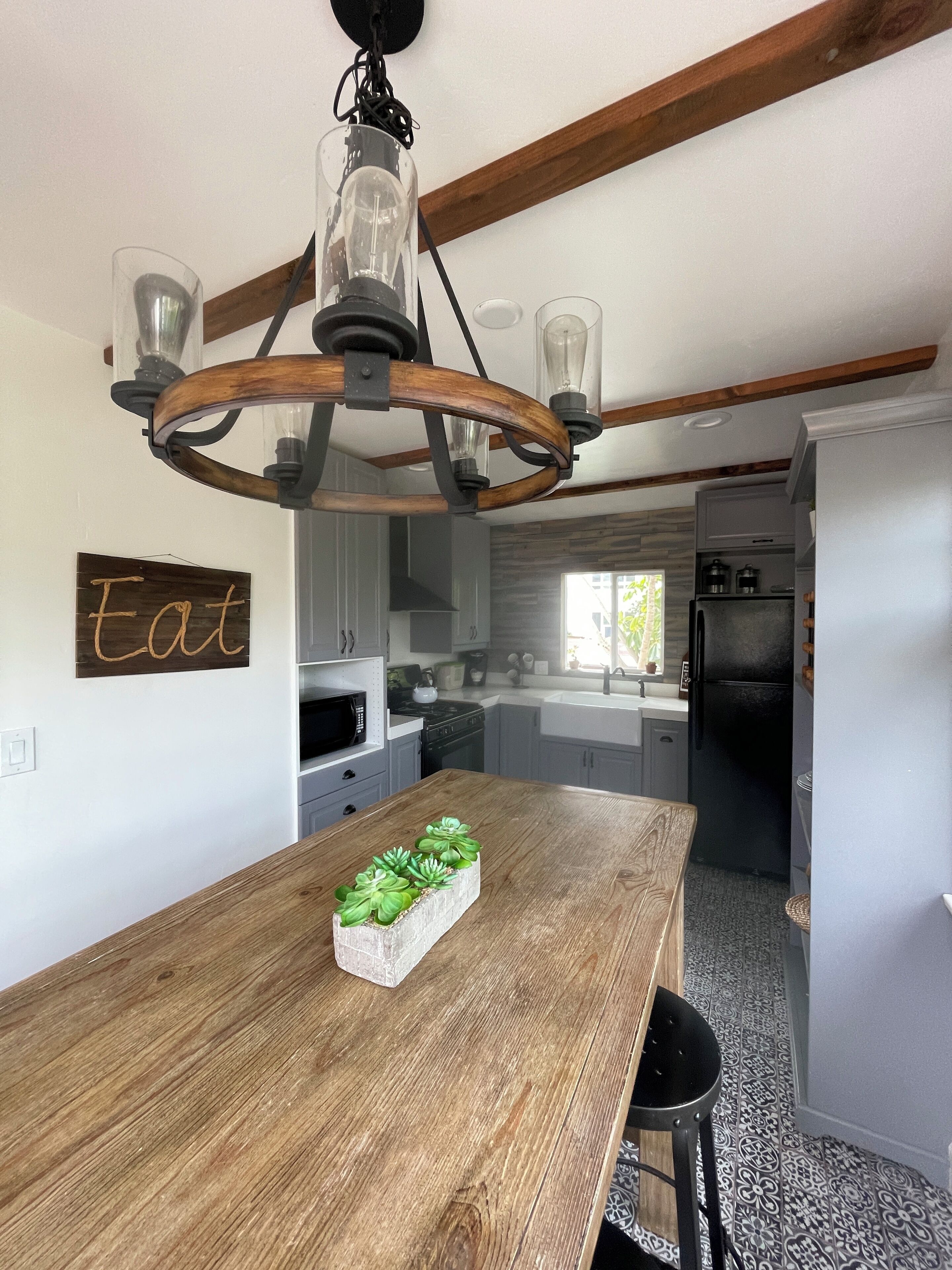 A modern kitchen with a wooden dining table, a built-in oven, and a black refrigerator.