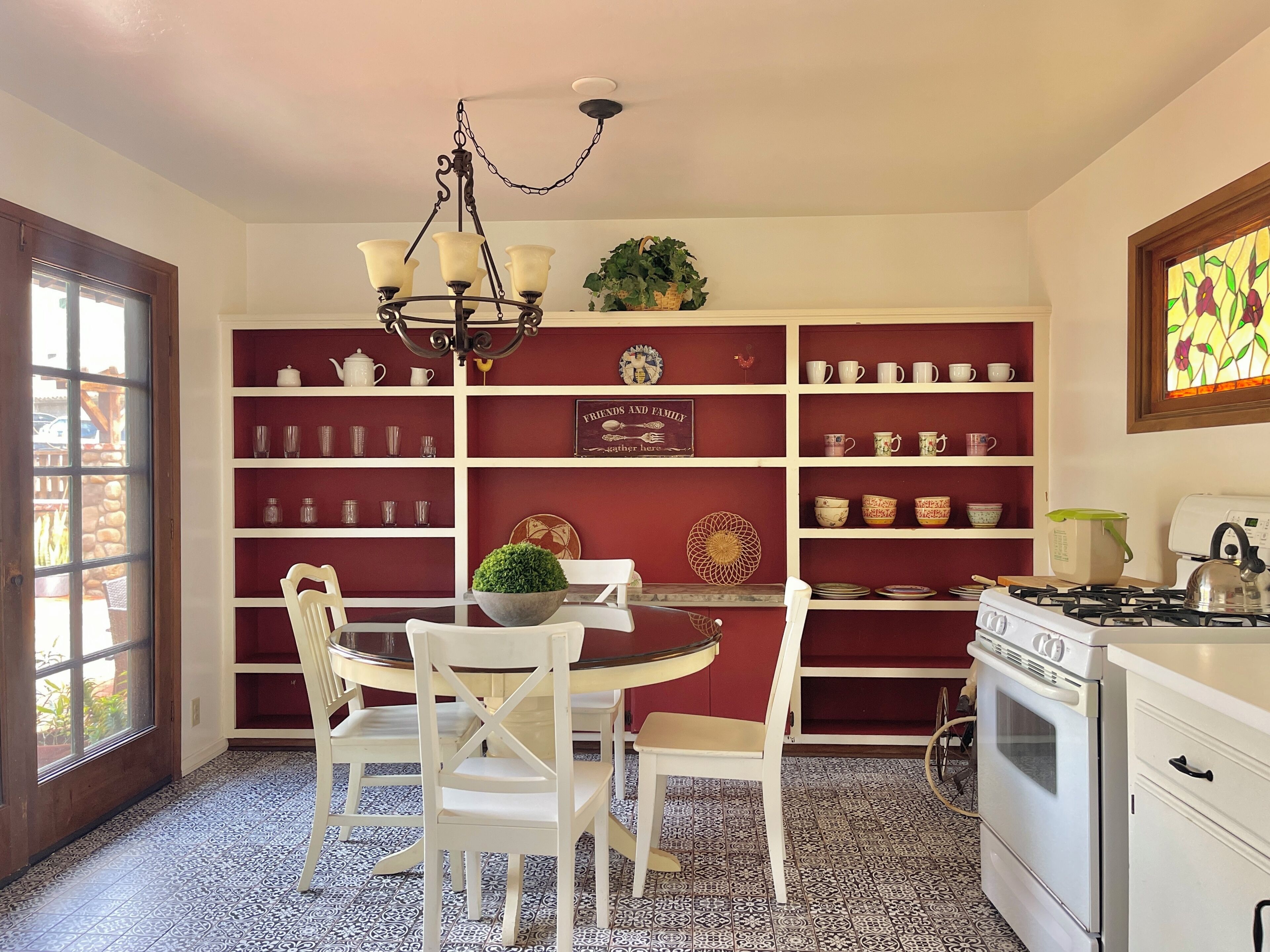 A kitchen with white cabinets, a gas stove, and a dining area with white chairs and a table.