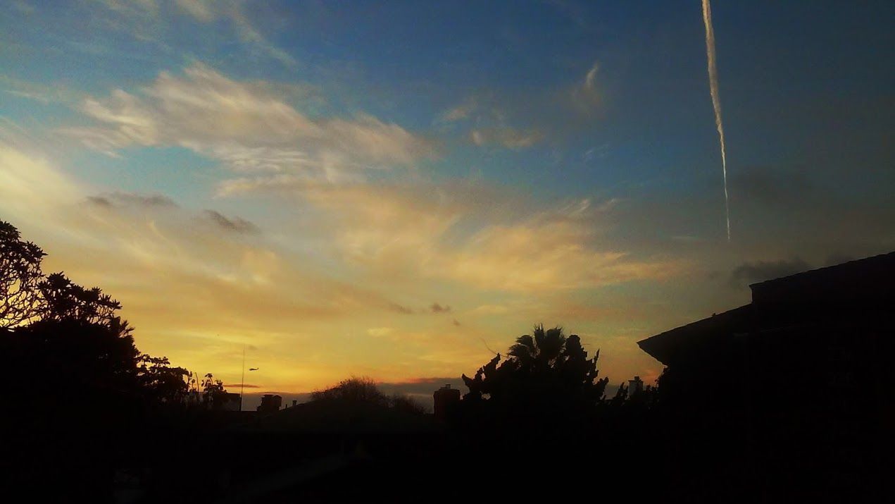 A sunset with a visible contrail in the sky.