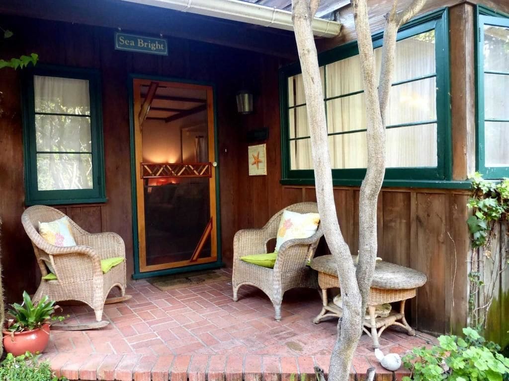 A wooden porch with wicker chairs and a brick floor.