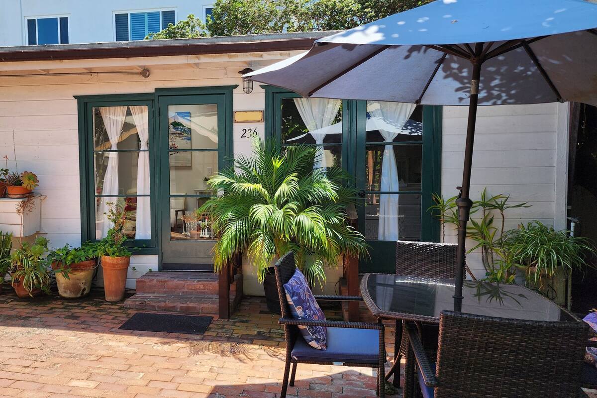 Un patio con mesa y sillas, plantas en macetas y un edificio con el número 236.