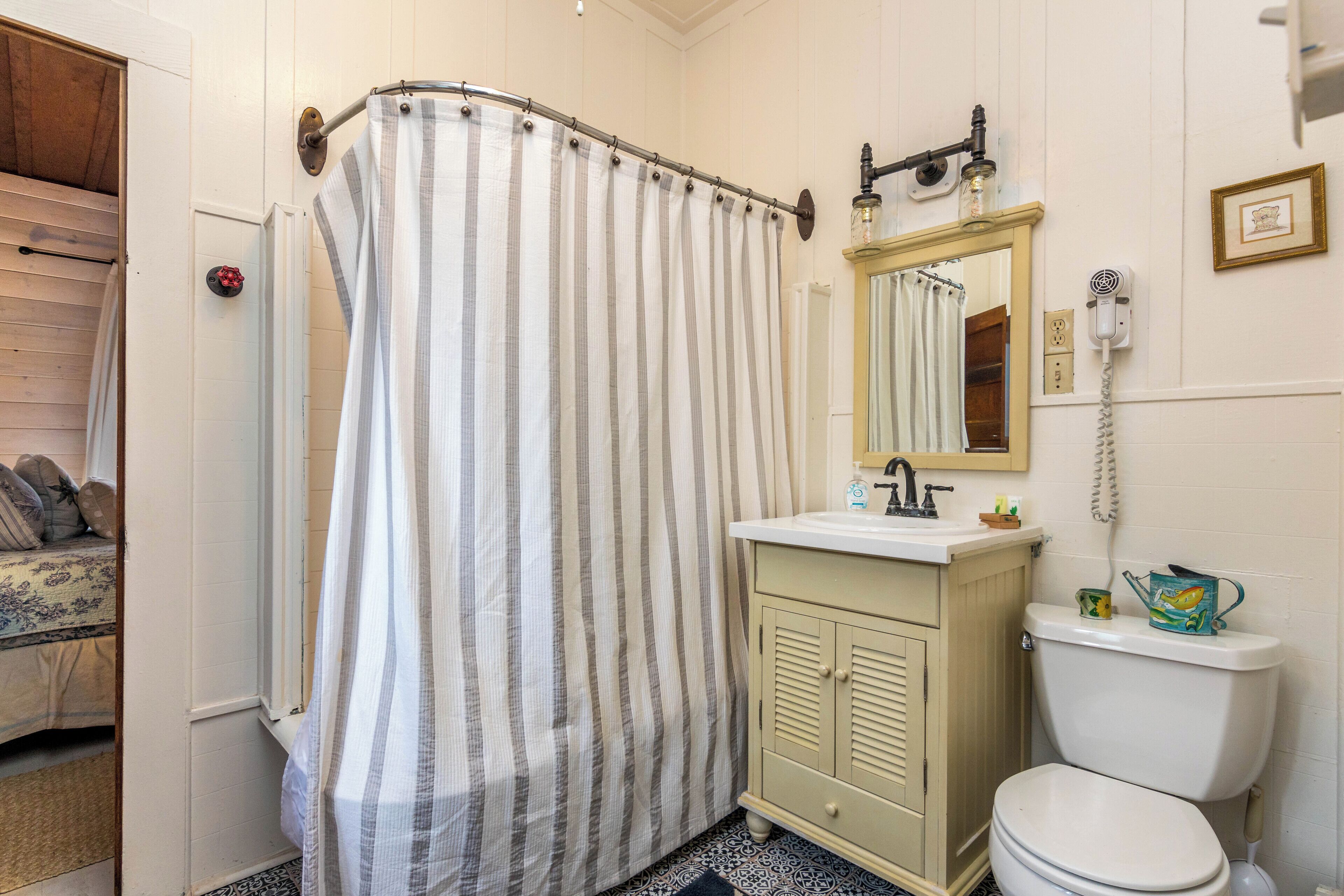 A bathroom with a striped shower curtain, a sink with a mirror above it, and a toilet.