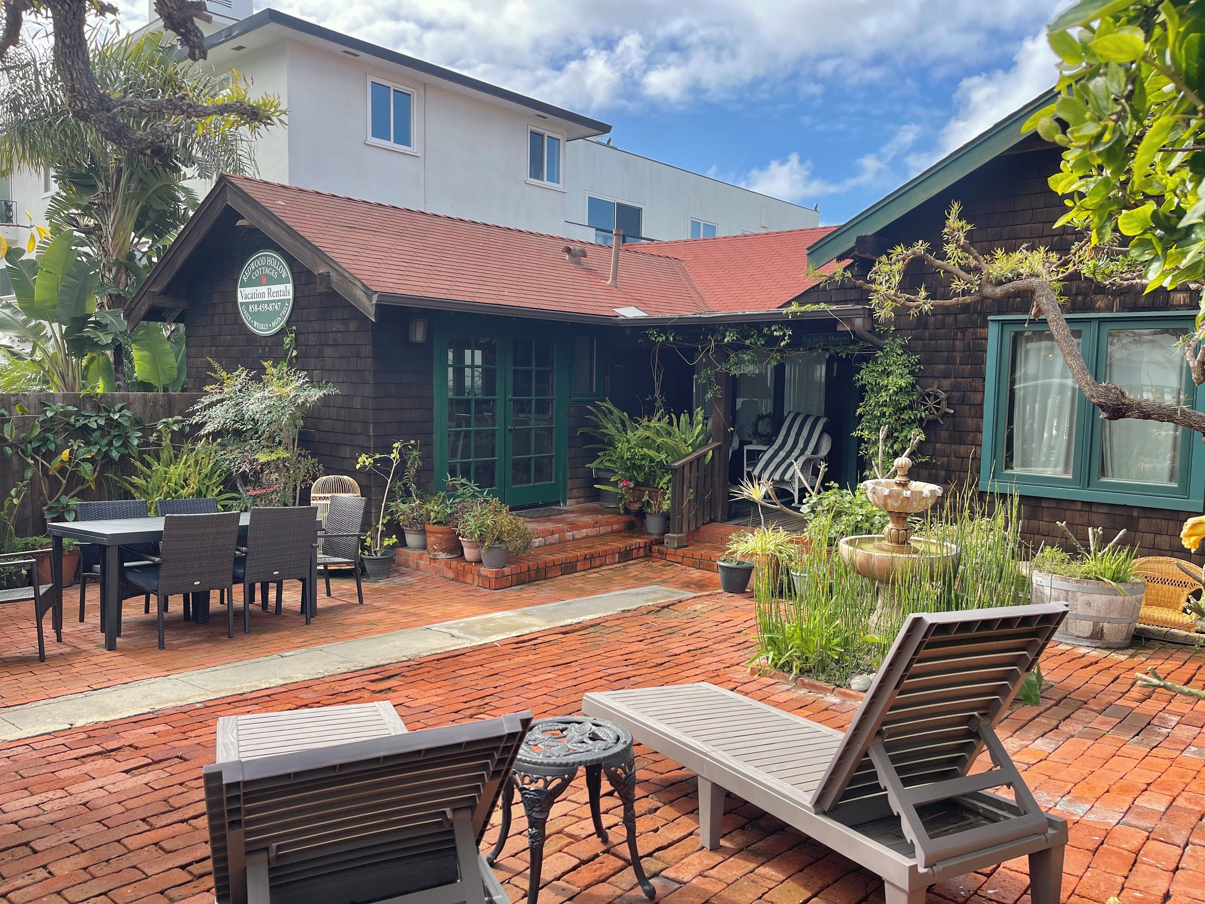 A patio area with outdoor seating, a wooden fence, and potted plants.