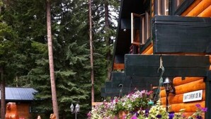 A wooden deck with a railing, surrounded by trees. - Mount Robson Mountain River Lodge (Mount Robson)