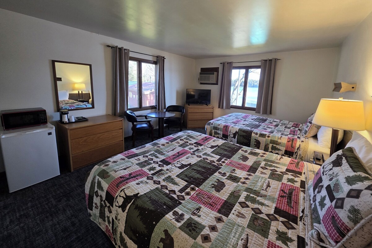 Een hotelkamer met twee bedden, een bureau, een stoel, een televisie en een magnetron.