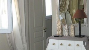 Une pièce avec une commode blanche, un miroir et une lampe.