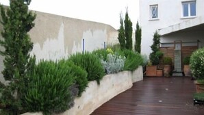 Une terrasse en bois avec un petit muret et différentes plantes.
