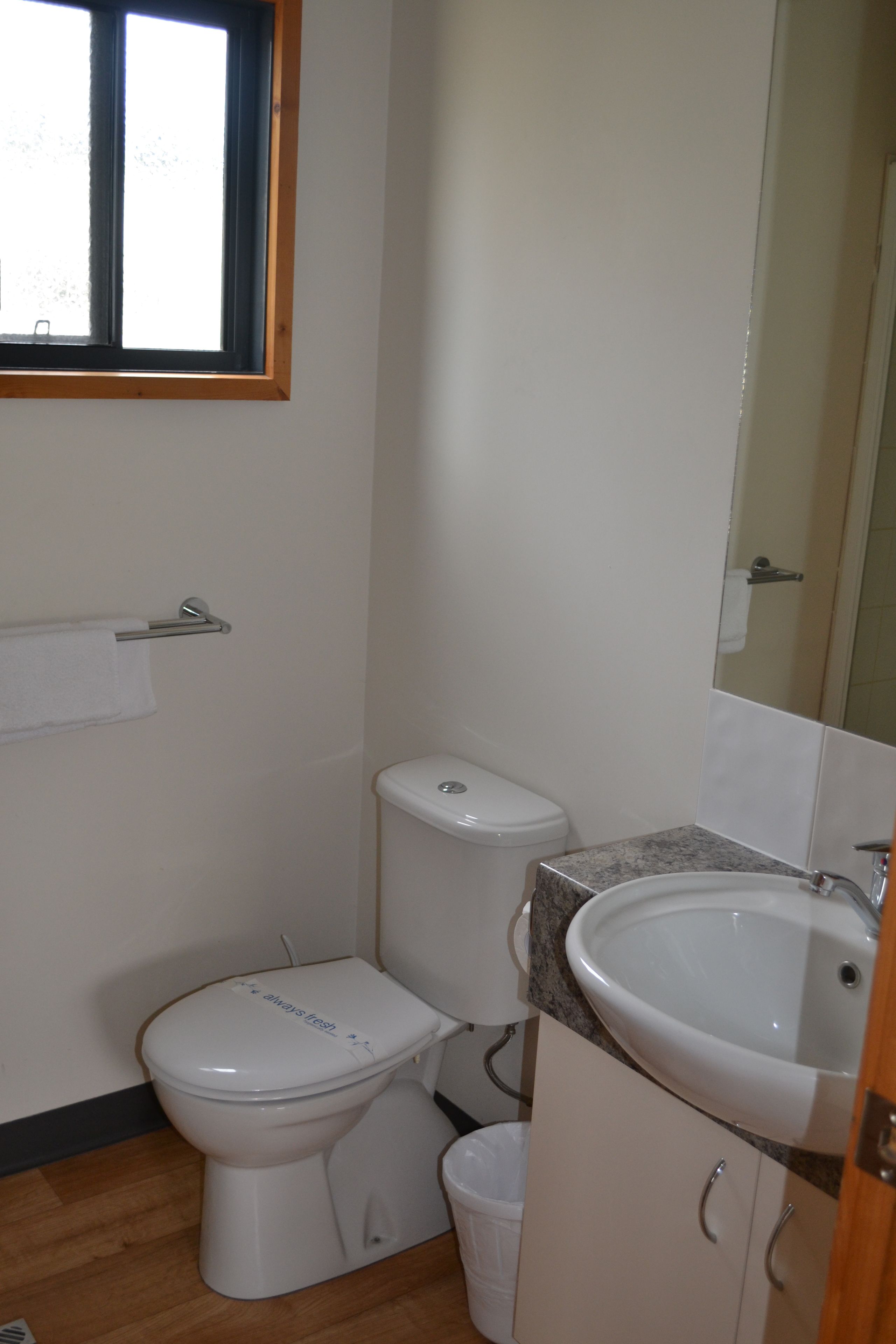 Un baño pequeño con inodoro, lavamanos y espejo.