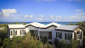 A beachfront property with multiple buildings, including a central structure with a balcony and a smaller attached building.