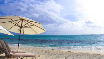 Una playa con una silla y una sombrilla.