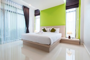 Una camera d'hotel moderna con un letto grande, una parete verde decorativa e vista sulla città.