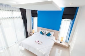 A modern hotel room with a large bed, white bedding, and a blue accent wall. - Jinda Resort (Sa Khu)