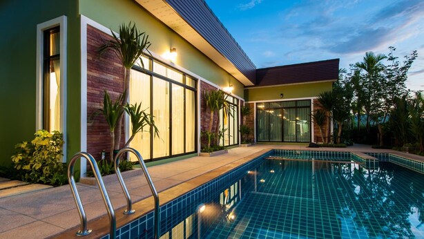 A modern hotel with a swimming pool, large windows, and a well-maintained garden. - Jinda Resort (Sa Khu)