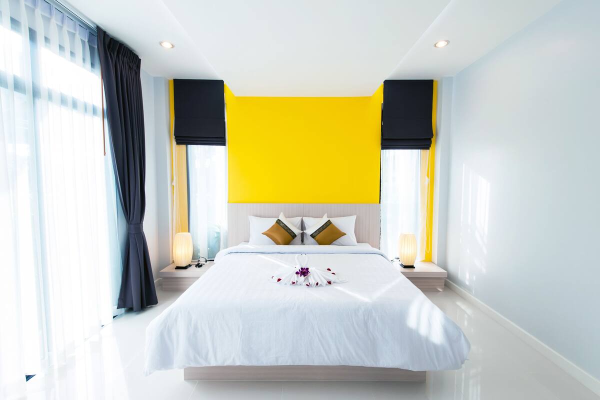 Una habitación de hotel con una cama grande, una pared de acento amarillo brillante y un diseño moderno.