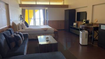 A modern room with a bed, sofa, desk, and a large window.