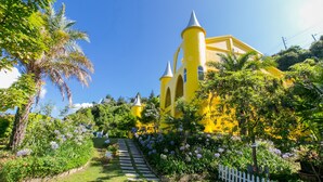 A yellow building with a tower, surrounded by lush greenery and flowers. - Cingjing Brilliant Twins of Seattle (Ren'ai)