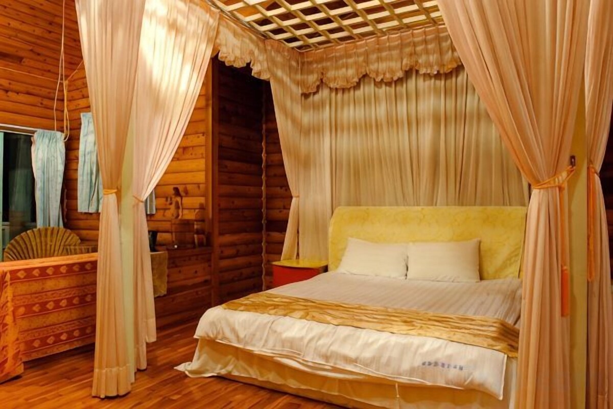 A wooden room with a bed, a nightstand, and a canopy bed.