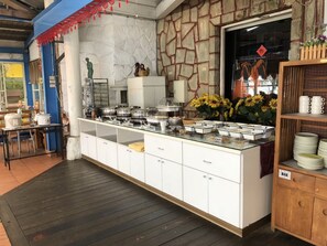 A buffet setup with various food containers and a statue on the counter. - Cingjing Brilliant Twins of Seattle (Ren'ai)