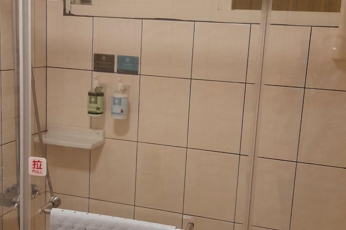 Un baño con baldosas color beige, un perchero y dos botellas sobre una repisa.