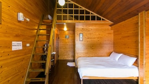 A wooden cabin room with a bed, a ladder, a small table, and a wall-mounted light fixture. - Cingjing Brilliant Twins of Seattle (Ren'ai)