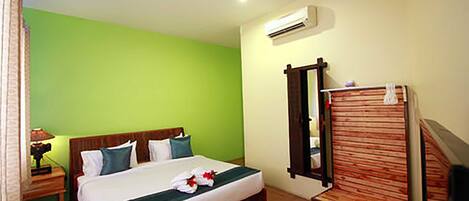 Habitación de hotel con cama, mesita de noche, unidad de aire acondicionado, espejo y banco de madera.