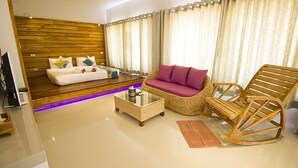 A modern living room with a sofa, a rocking chair, and a coffee table. - Good Times Resort (Kanchanaburi)