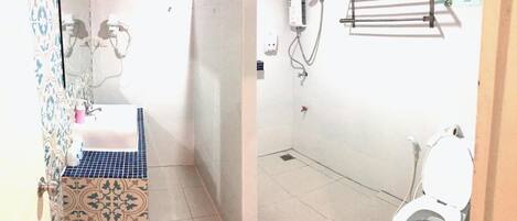 Un baño con suelo de baldosas, un lavabo con salpicadero decorado y un inodoro, además de una zona de ducha.